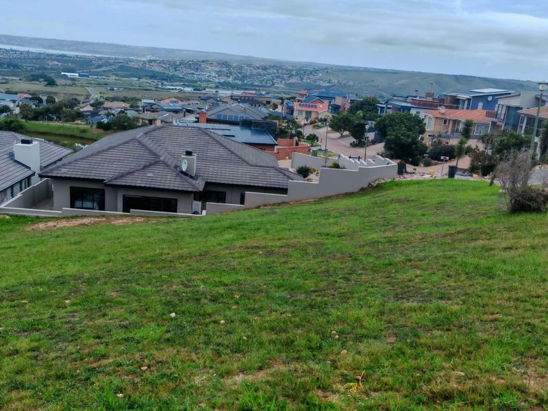 Elevated view overlooking a residential neighborhood and surrounding landscape from a sloped vacant residential plot.