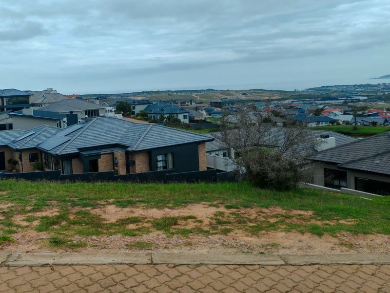 An elevated view overlooking a residential estate with modern homes and distant coastal landscape.