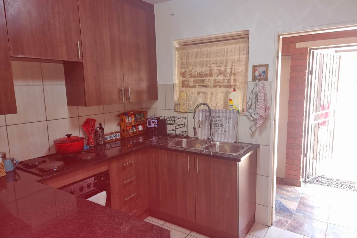 Functional kitchen featuring laminate cabinetry, granite countertops, built-in oven and hob, and a double bowl stainless steel sink with tiled finishes.