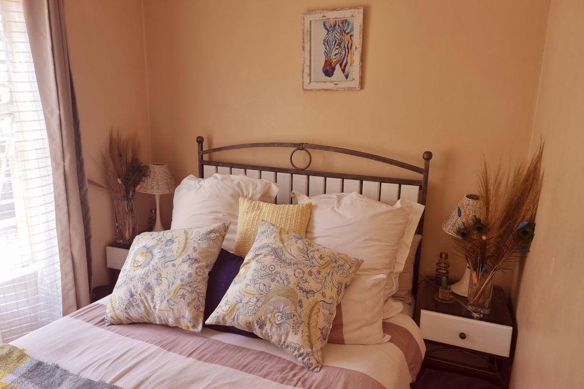 A cozy bedroom featuring neutral wall tones and natural light from the side window.