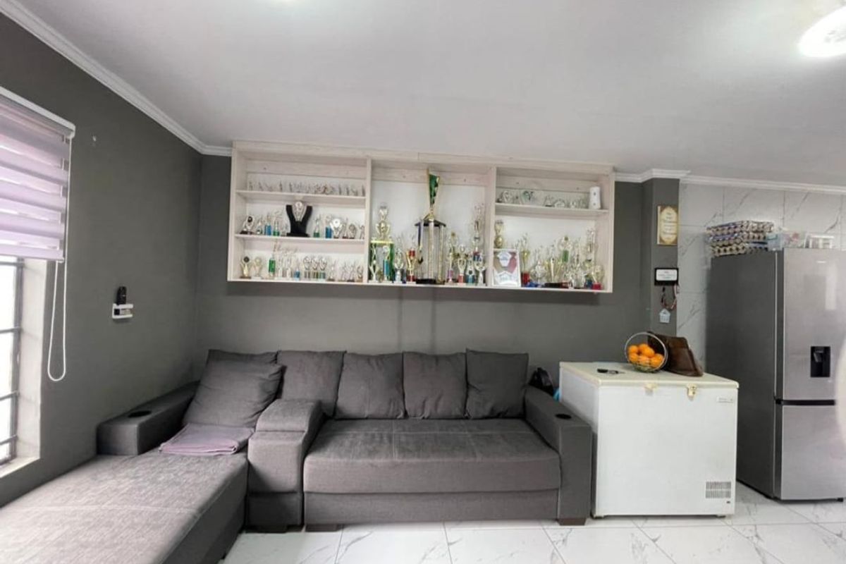 A living area featuring modern tiled flooring, built-in wall shelving, and neutral grey wall finishes.