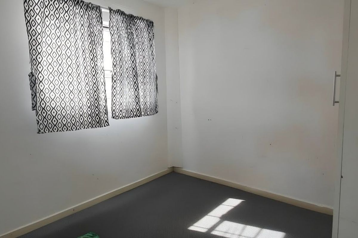 An empty bedroom featuring carpet flooring and a built-in wardrobe, requiring minor cosmetic updates to the wall finishes.