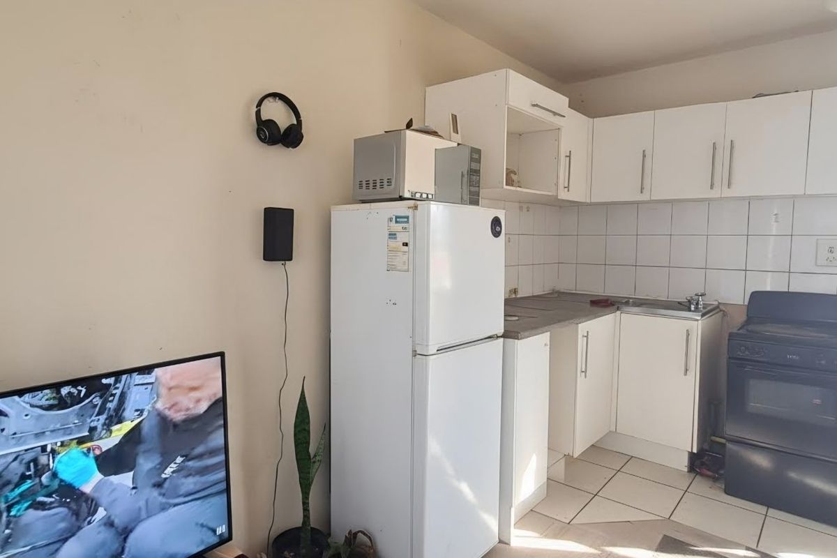 A compact kitchen featuring white cabinetry, tiled backsplash, and a freestanding oven, offering a functional layout with potential for cosmetic updates.