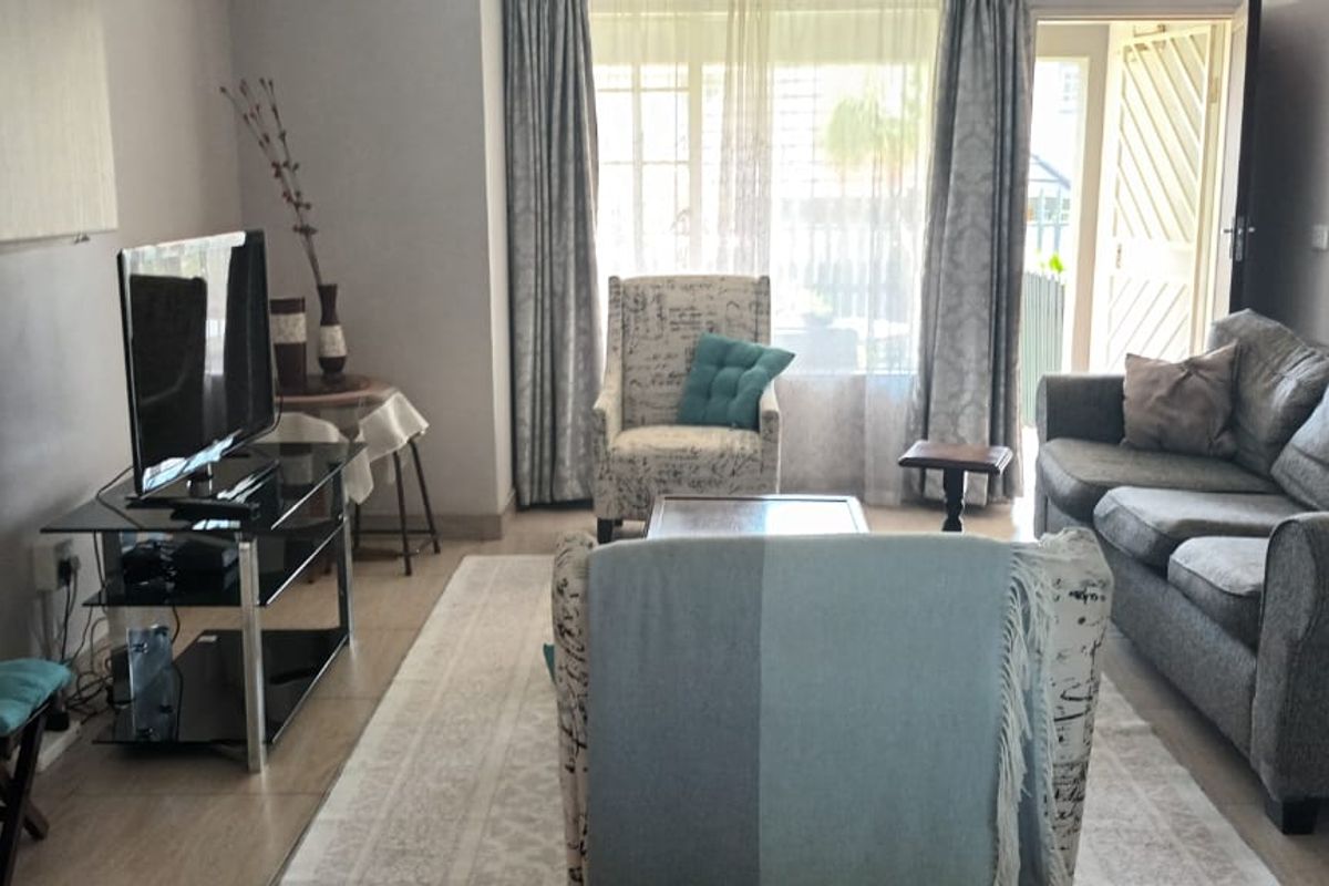 A comfortable living room featuring tiled flooring and a sliding glass door that provides access to the outdoor area.