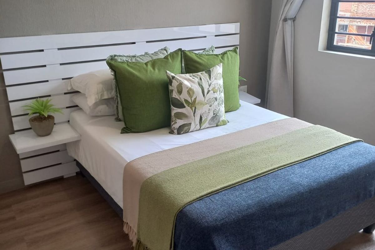 A well-maintained bedroom featuring durable laminate flooring and a window fitted with security bars for added peace of mind.