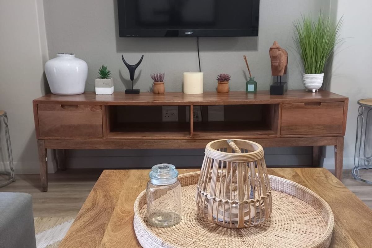 A well-maintained living room area featuring laminate flooring and a wall-mounted television setup.