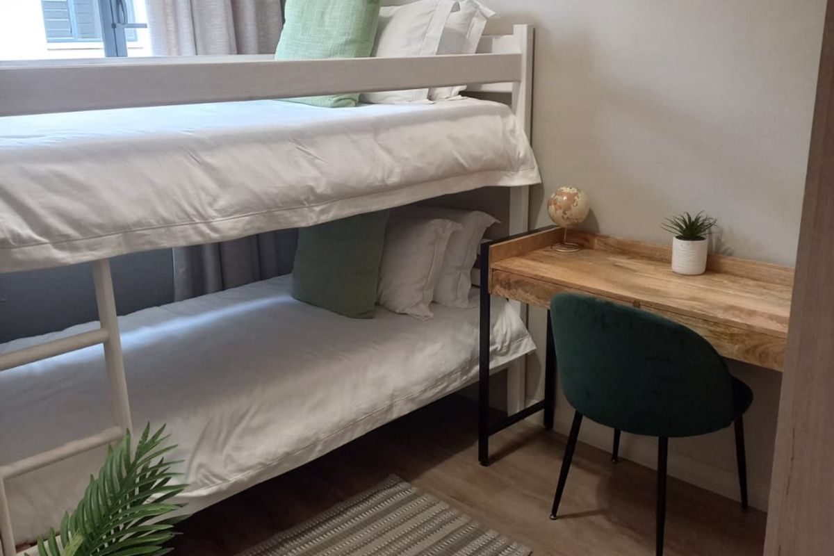 A well-maintained bedroom featuring laminate flooring, neutral wall tones, and a window with curtain fixtures.