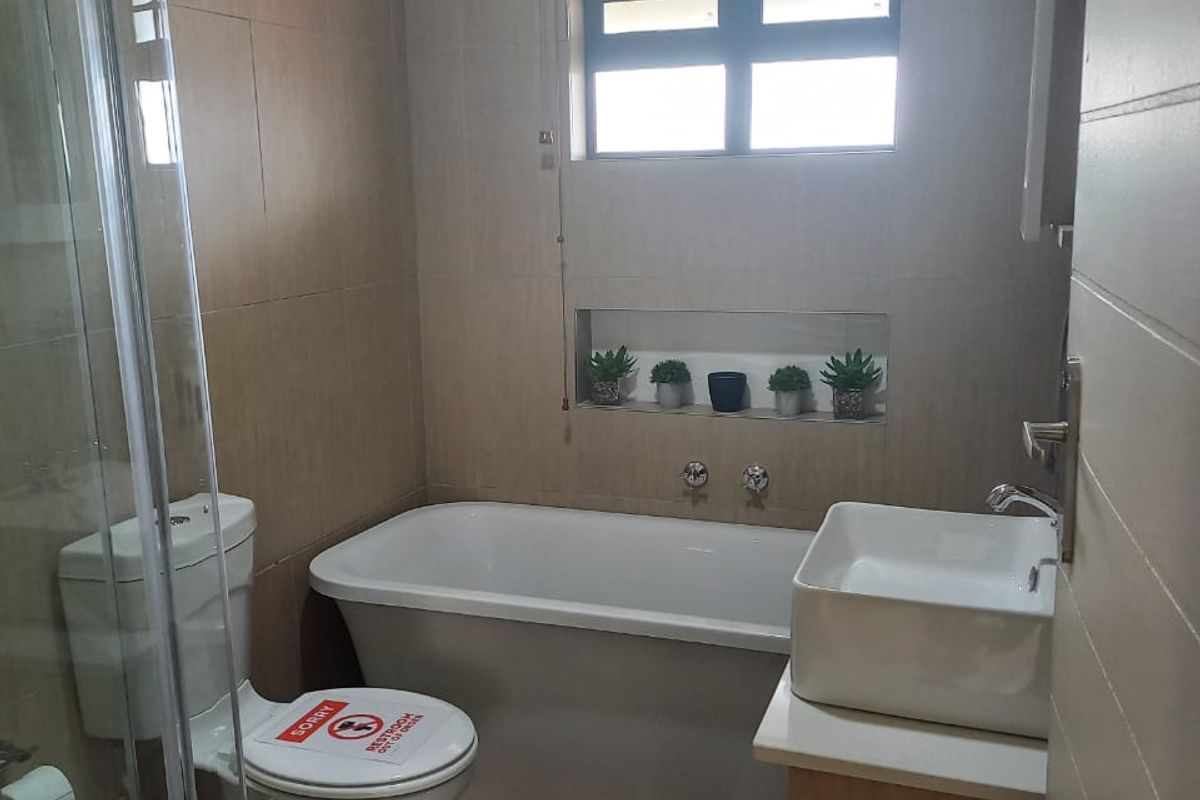 Modern bathroom featuring a freestanding bathtub, glass-enclosed shower, vessel sink vanity, and a convenient recessed wall niche for storage.