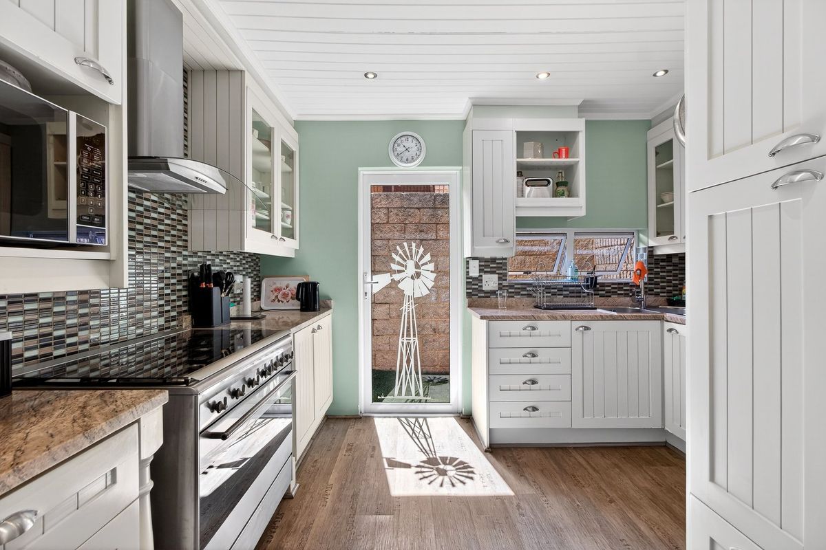 A well-maintained kitchen featuring white cabinetry, mosaic tile backsplash, stainless steel appliances, and direct access to an outdoor area.
