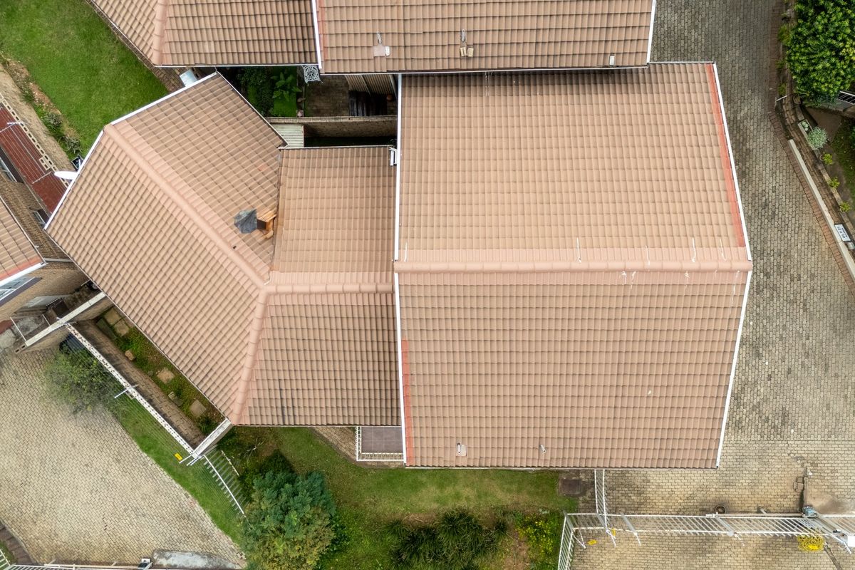 Aerial view of the townhouse property showcasing the tiled roof structure, paved driveway, and surrounding garden areas.