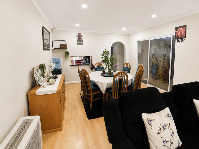 Open plan living and dining area featuring laminate flooring, recessed lighting, and a convenient pass-through window connecting to the kitchen space.