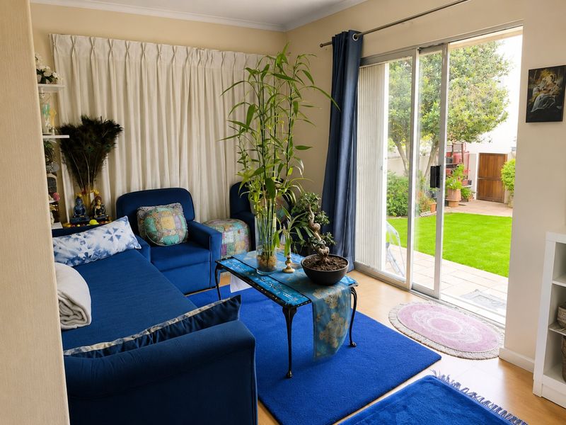 A bright living room featuring laminate flooring and large sliding glass doors that provide direct access to the rear garden area.