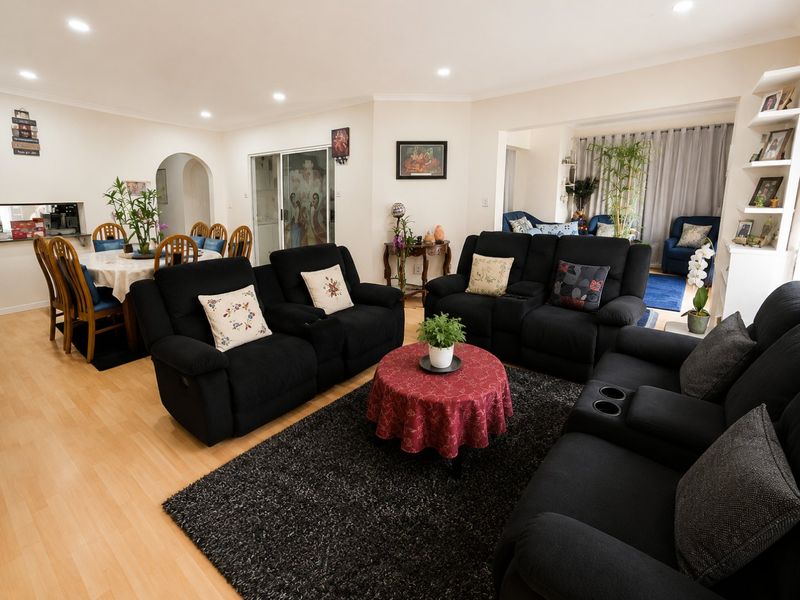 Spacious open-plan living and dining area featuring laminate flooring, recessed lighting, and an archway leading to adjacent rooms.