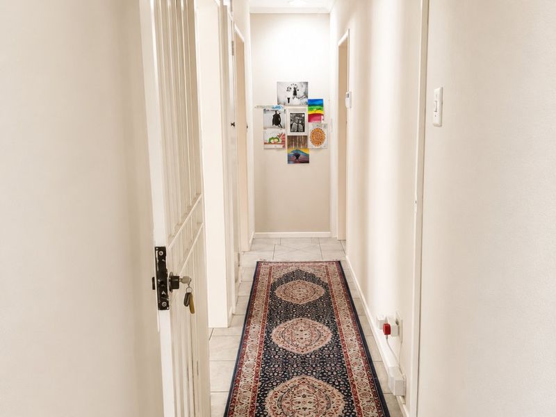 A clean and well-maintained hallway featuring tiled flooring and a secure metal gate at the entrance.