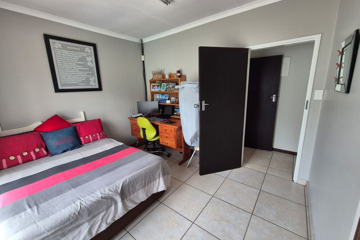 A functional bedroom featuring tiled flooring and neutral wall finishes, providing a practical space with direct access to an adjoining hallway.