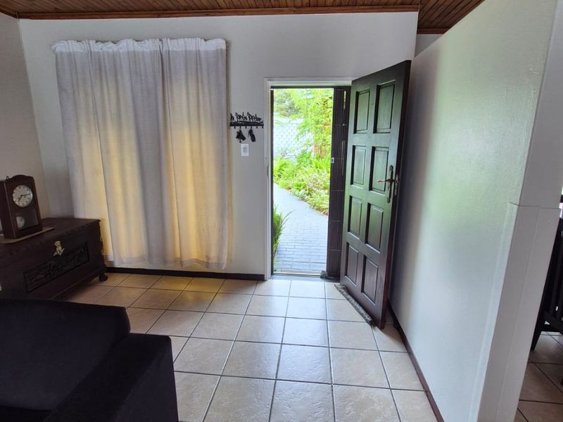 Entrance area featuring ceramic floor tiles and a timber tongue and groove ceiling, providing direct access to the exterior garden path.
