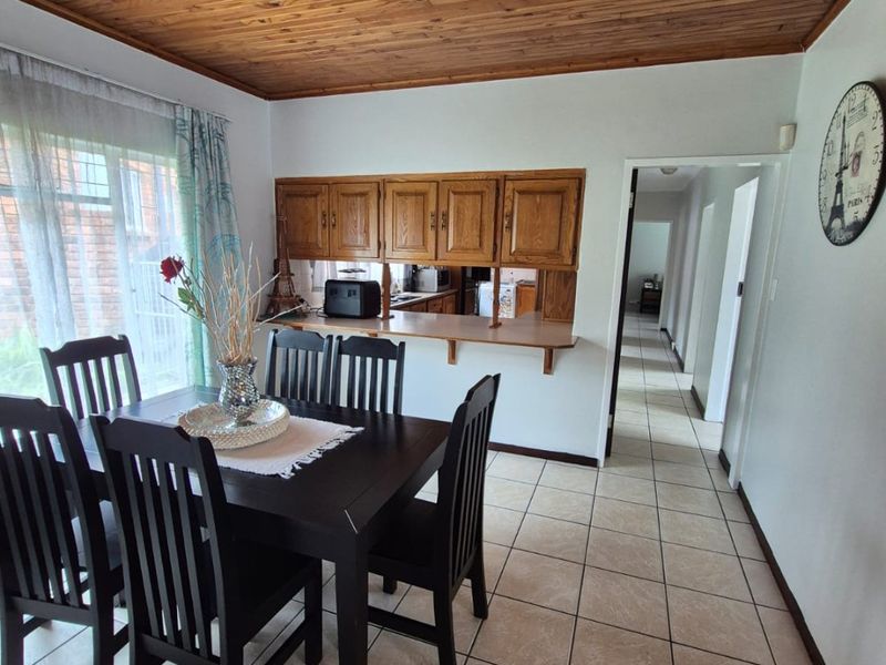 Dining area featuring a timber-clad ceiling, ceramic floor tiles, and a convenient pass-through window connecting to the kitchen.
