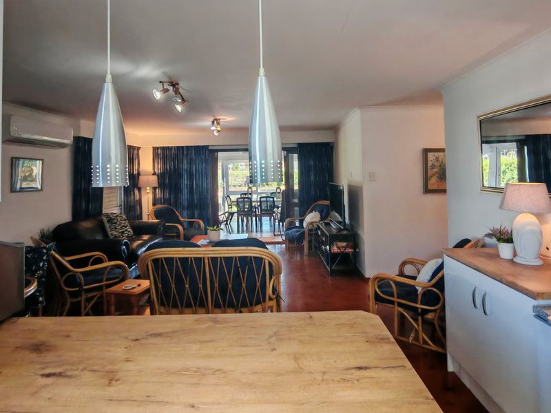 Spacious open-plan living area featuring pendant lighting, split-system air conditioning, and direct access to the outdoor patio through sliding glass doors.