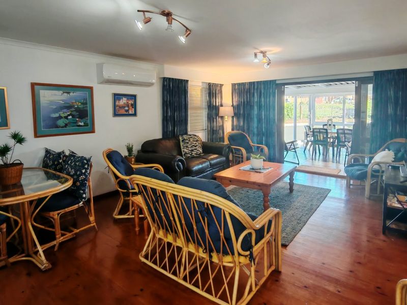 Spacious living room featuring polished hardwood flooring, a wall-mounted air conditioning unit, and large sliding glass doors providing access to the outdoor patio area.