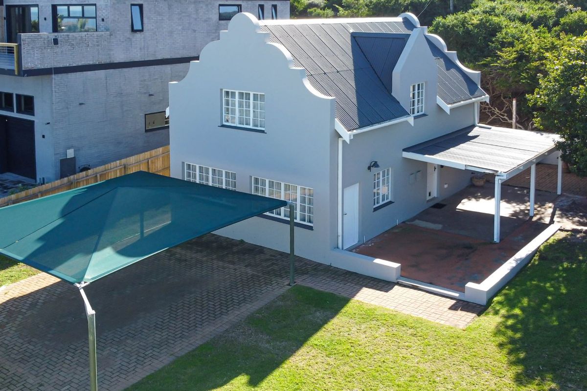 Aerial view of the property featuring a gabled roof design, paved driveway with shade sail, and a covered rear patio area.