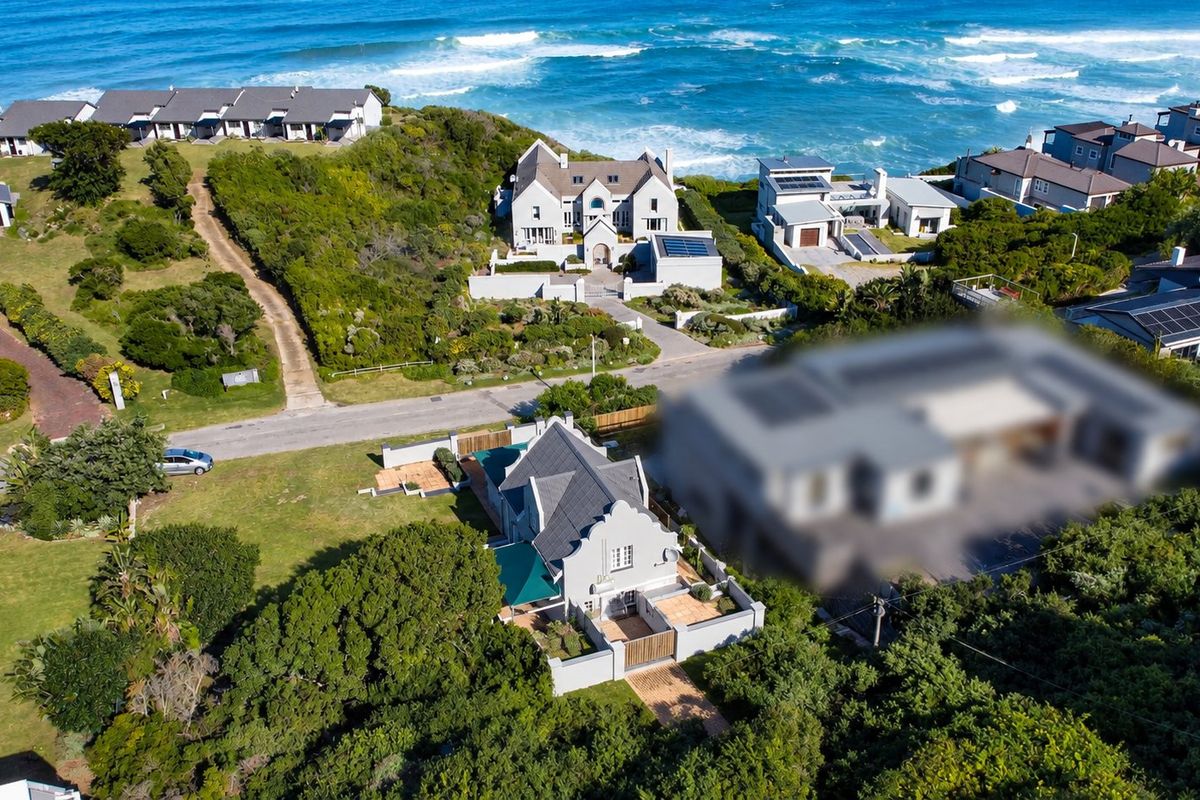 Aerial view of a coastal residential estate featuring well-maintained homes, landscaped gardens, and proximity to the ocean.
