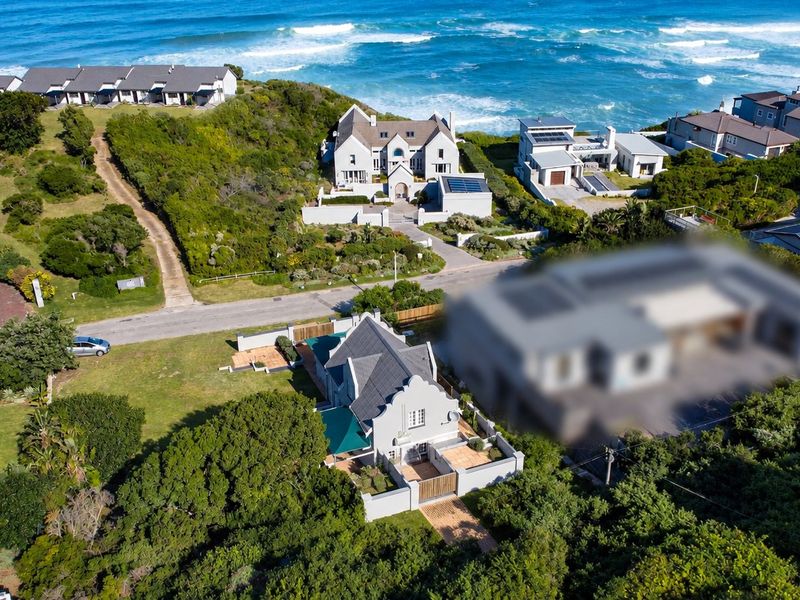 Aerial view of a coastal residential estate featuring well-maintained homes, landscaped gardens, and proximity to the ocean.