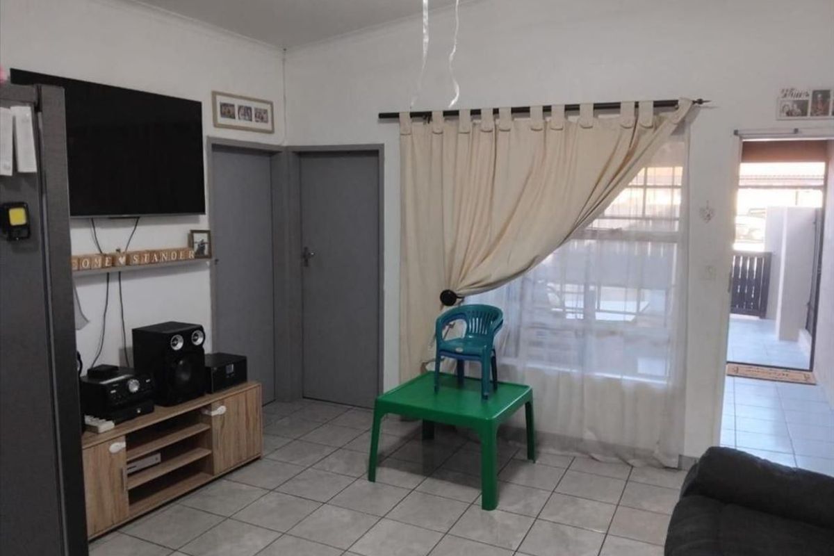 A living room area featuring tiled flooring, neutral wall finishes, and access to an outdoor patio area.