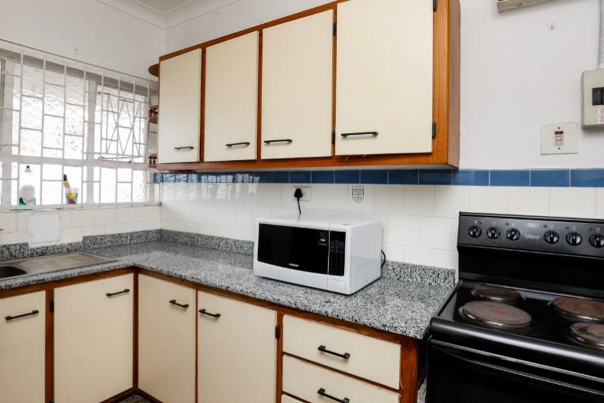 A functional kitchen featuring granite countertops, built-in cabinetry, and a freestanding electric stove, offering a practical layout with potential for modern updates.
