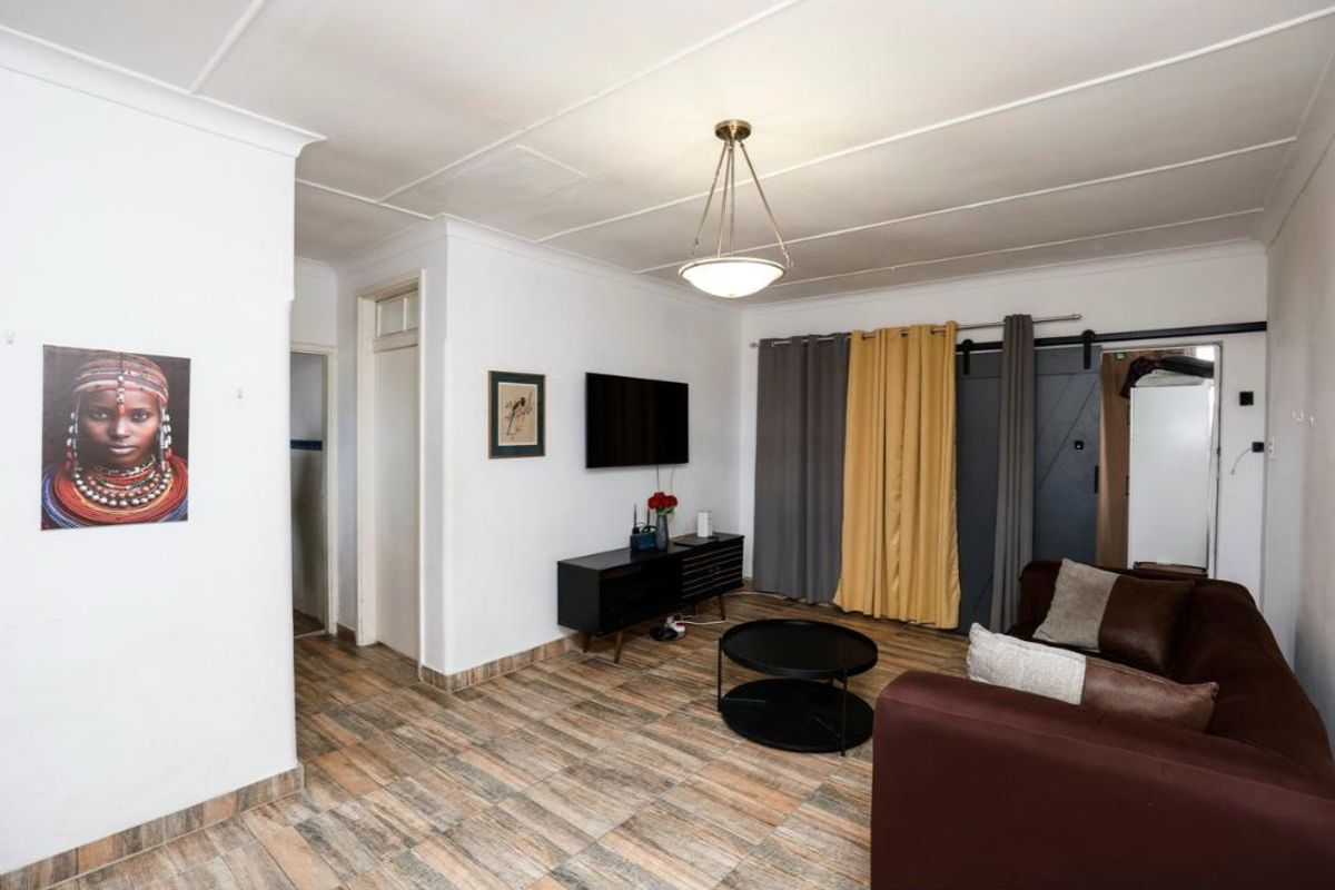 A living room featuring tiled flooring, a sliding barn door, and a coved ceiling, providing a functional and neutral living space.