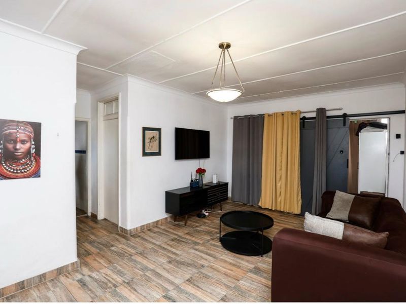 A living room featuring tiled flooring, a sliding barn door, and a coved ceiling, providing a functional and neutral living space.