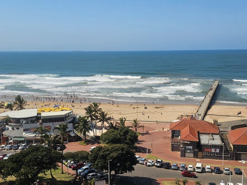 Elevated panoramic view overlooking the beach, ocean, piers, and surrounding coastal infrastructure.