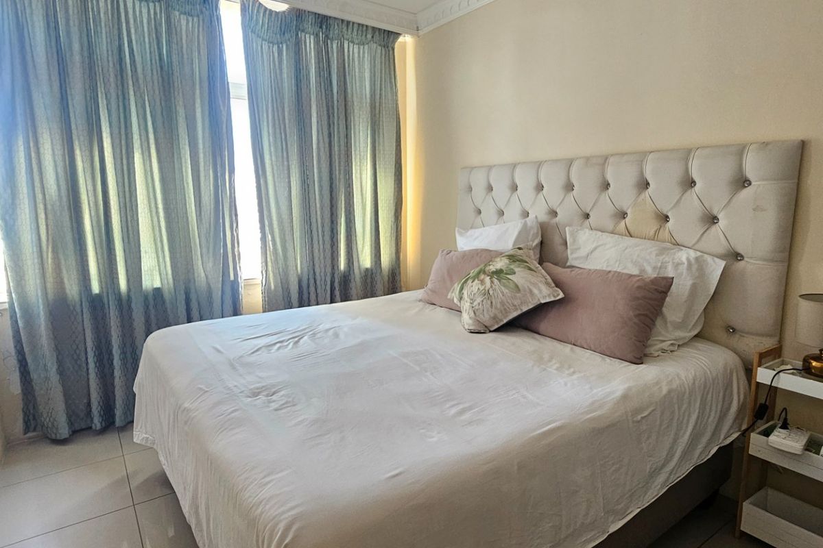 A bedroom featuring tiled flooring and decorative cornice detailing, providing a functional space with natural light from the window.