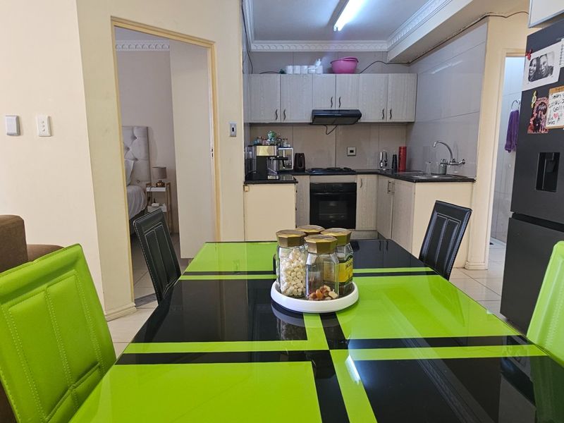 Open-plan living and dining area featuring a compact kitchen with built-in cabinetry, oven, hob, and extractor fan.