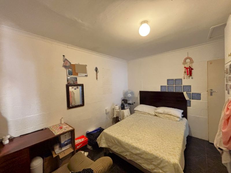 A compact bedroom featuring tiled flooring and coved ceilings, currently requiring cosmetic updates to improve the overall finish and aesthetic appeal.