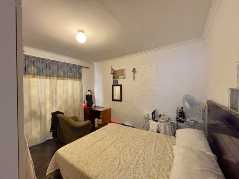 A functional bedroom featuring tiled flooring and simple cove cornice detailing, offering a blank canvas for potential interior updates.