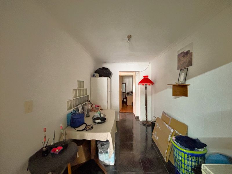 A narrow hallway featuring tiled flooring, a glass block feature wall, and coved ceiling details, providing access to adjacent rooms.