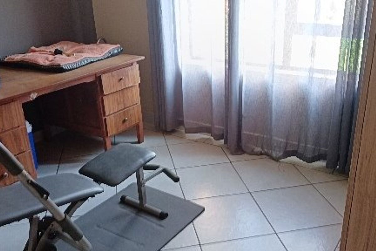 A bedroom featuring tiled flooring and a large window, providing natural light to the space.