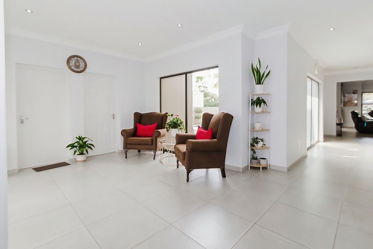 A bright and spacious living area featuring neutral tiled flooring, recessed downlighting, and large sliding glass doors providing natural light.