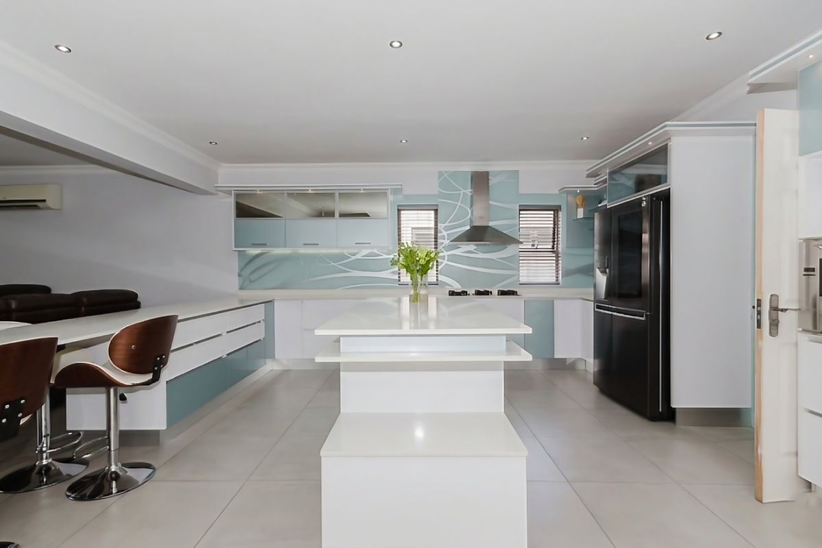 Modern kitchen featuring a central island, sleek cabinetry, integrated appliances, and contemporary tiled flooring with recessed lighting.