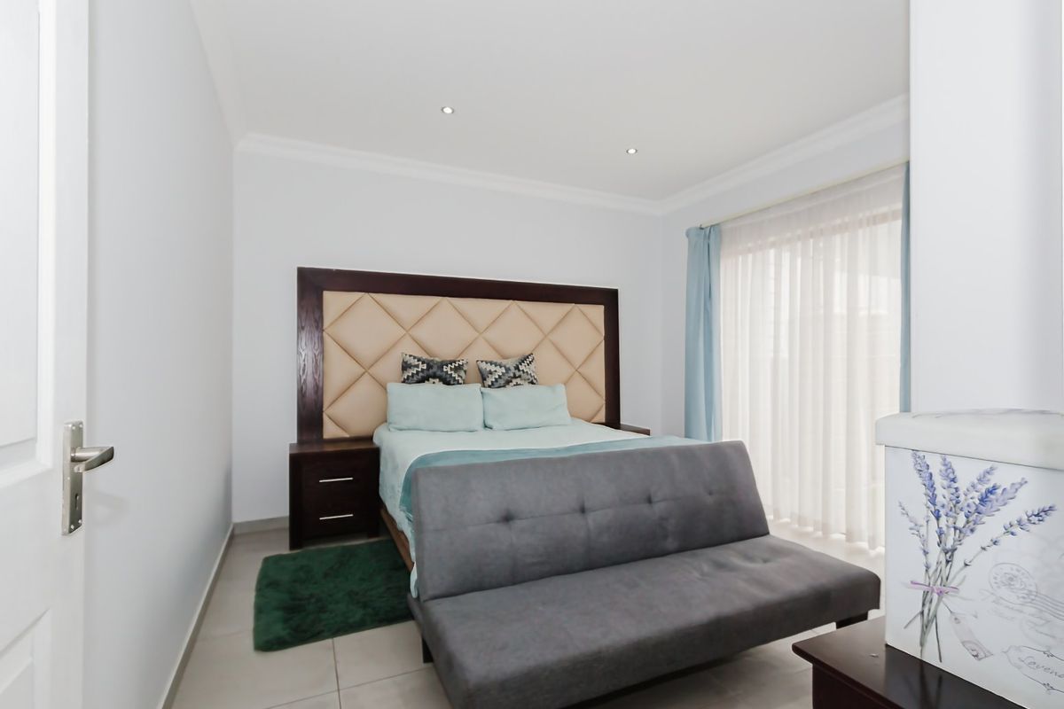A well-maintained bedroom featuring tiled flooring, recessed downlighting, and a large sliding glass door providing natural light.