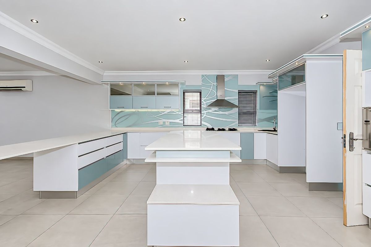 Modern kitchen featuring a central island, quartz countertops, sleek cabinetry, and integrated extractor fan, offering a clean and functional culinary space.