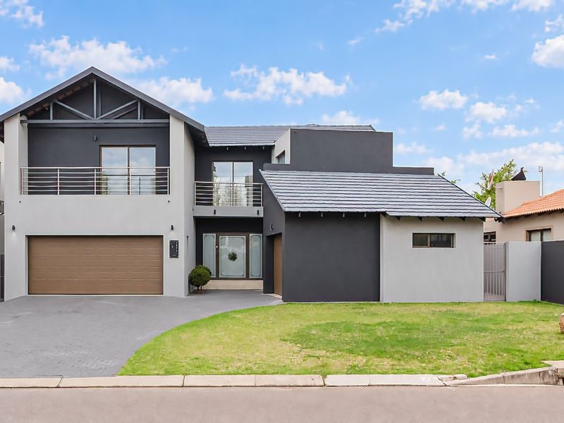 Modern double-story residential home featuring a contemporary facade, double garage, upper-level balcony, and a well-maintained front lawn and driveway.