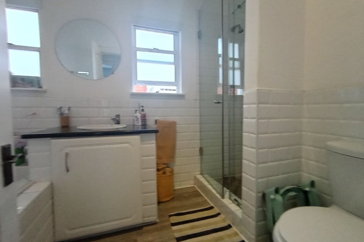 A functional bathroom featuring subway tile wall cladding, a glass shower enclosure, a vanity cabinet with a countertop basin, and a toilet.