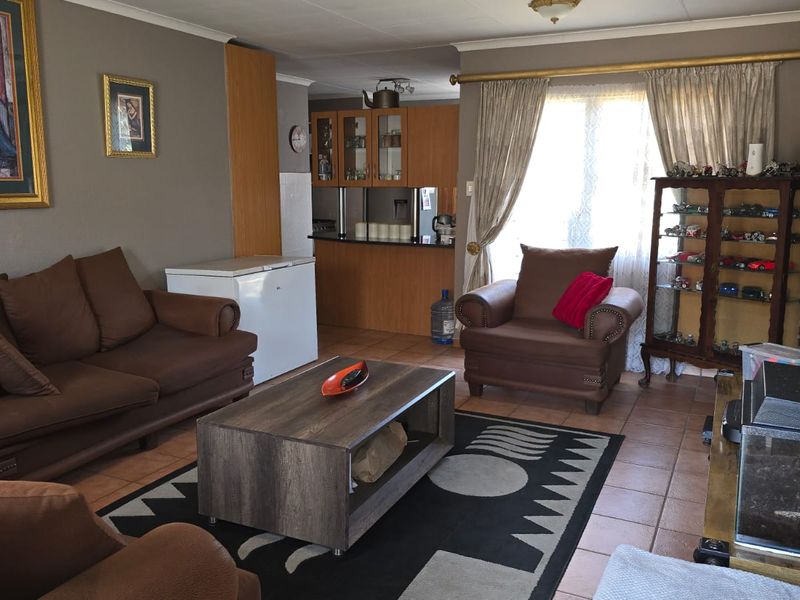Open plan living area featuring tiled flooring and a connected kitchen space with built-in cabinetry and a breakfast bar.