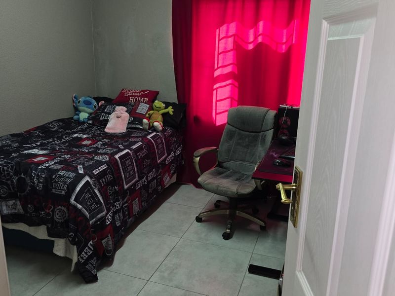 A functional bedroom featuring tiled flooring and a window, providing a comfortable space for rest or study.