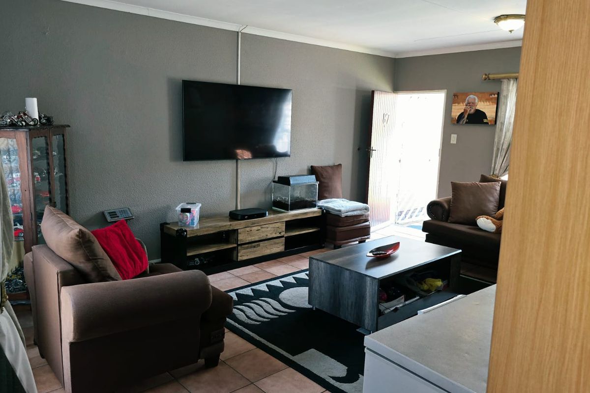 A comfortable living room featuring tiled flooring and direct access to the exterior, providing a functional and well-lit space for relaxation.