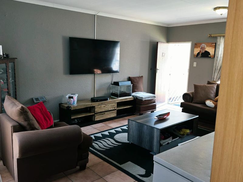 A comfortable living room featuring tiled flooring and direct access to the exterior, providing a functional and well-lit space for relaxation.