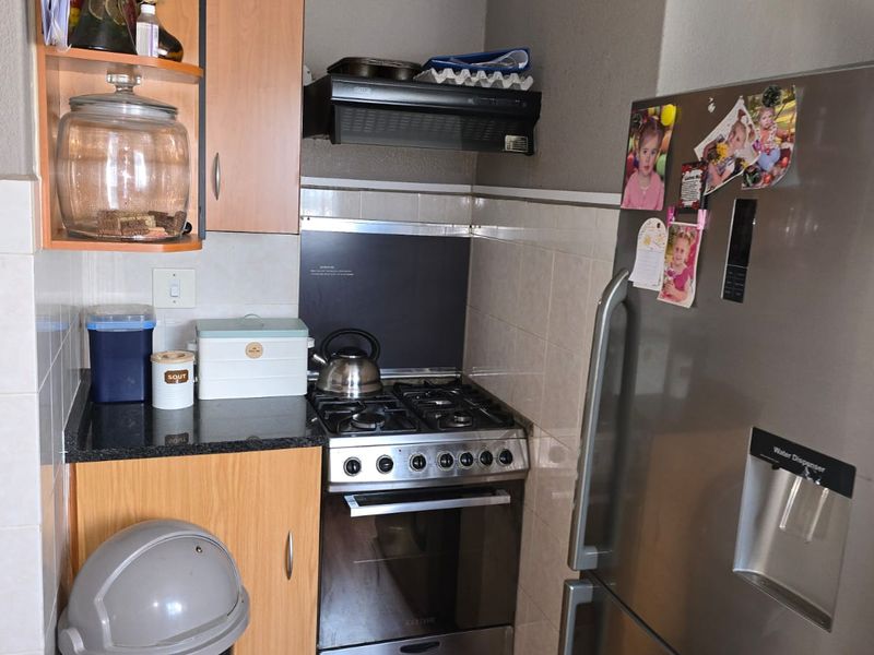 Compact kitchen featuring a gas stove, extractor fan, granite countertops, and tiled backsplash with built-in cabinetry.