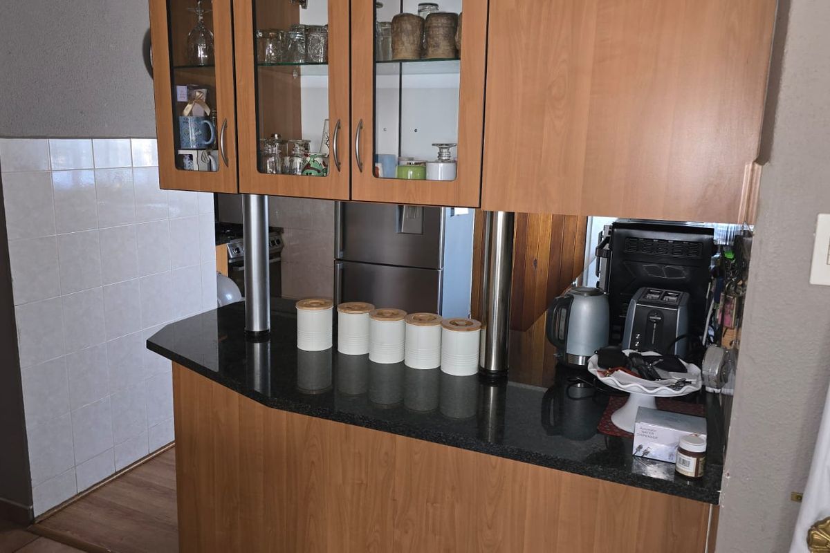 Kitchen area featuring laminate cabinetry, granite countertops, and a tiled splashback, providing a functional workspace with integrated storage solutions.