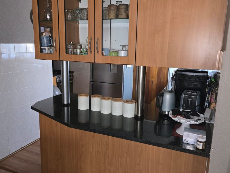 Kitchen area featuring laminate cabinetry, granite countertops, and a tiled splashback, providing a functional workspace with integrated storage solutions.